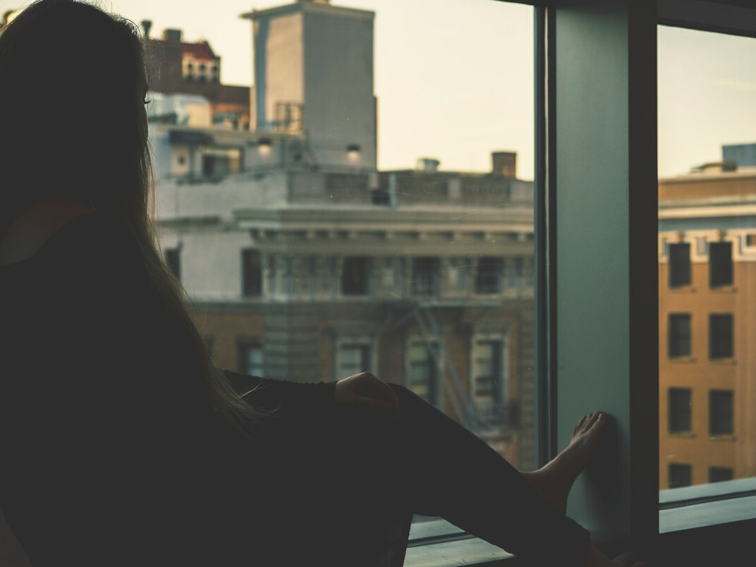 Anonyme Person von hinten an einem großen Fenster mit Blick nach draußen